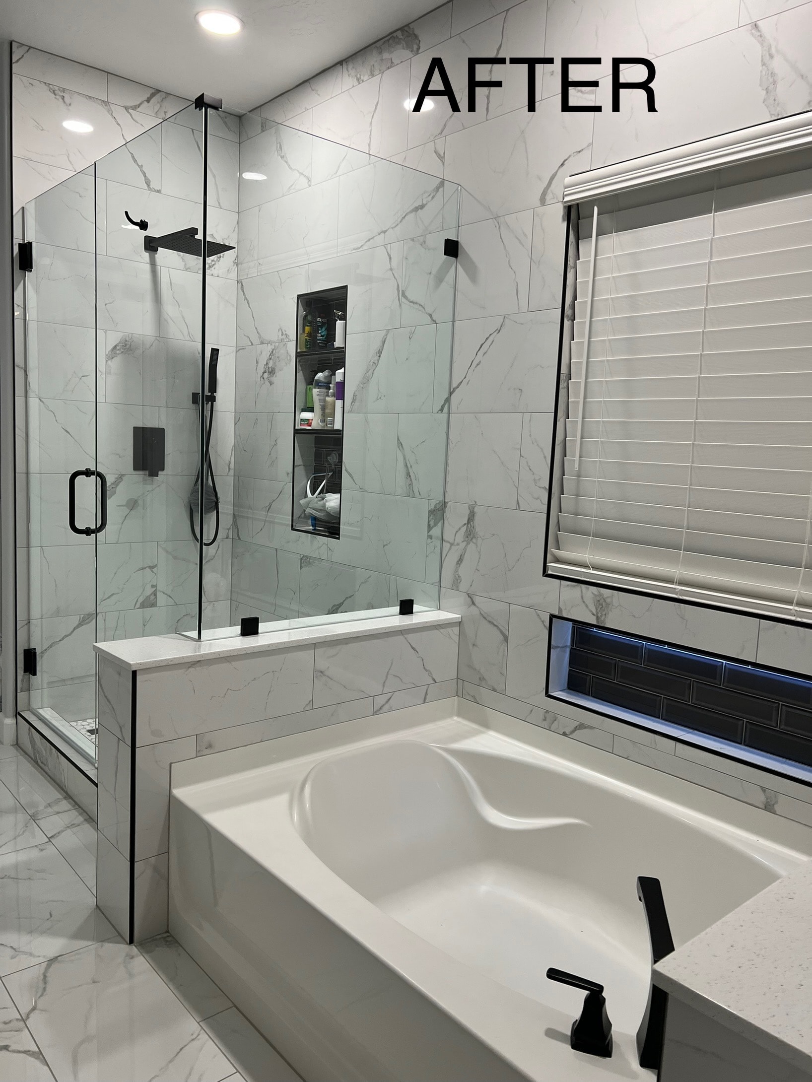 Bathroom remodel after — glass shower enclosure, marble tile, soaking tub, and black fixtures