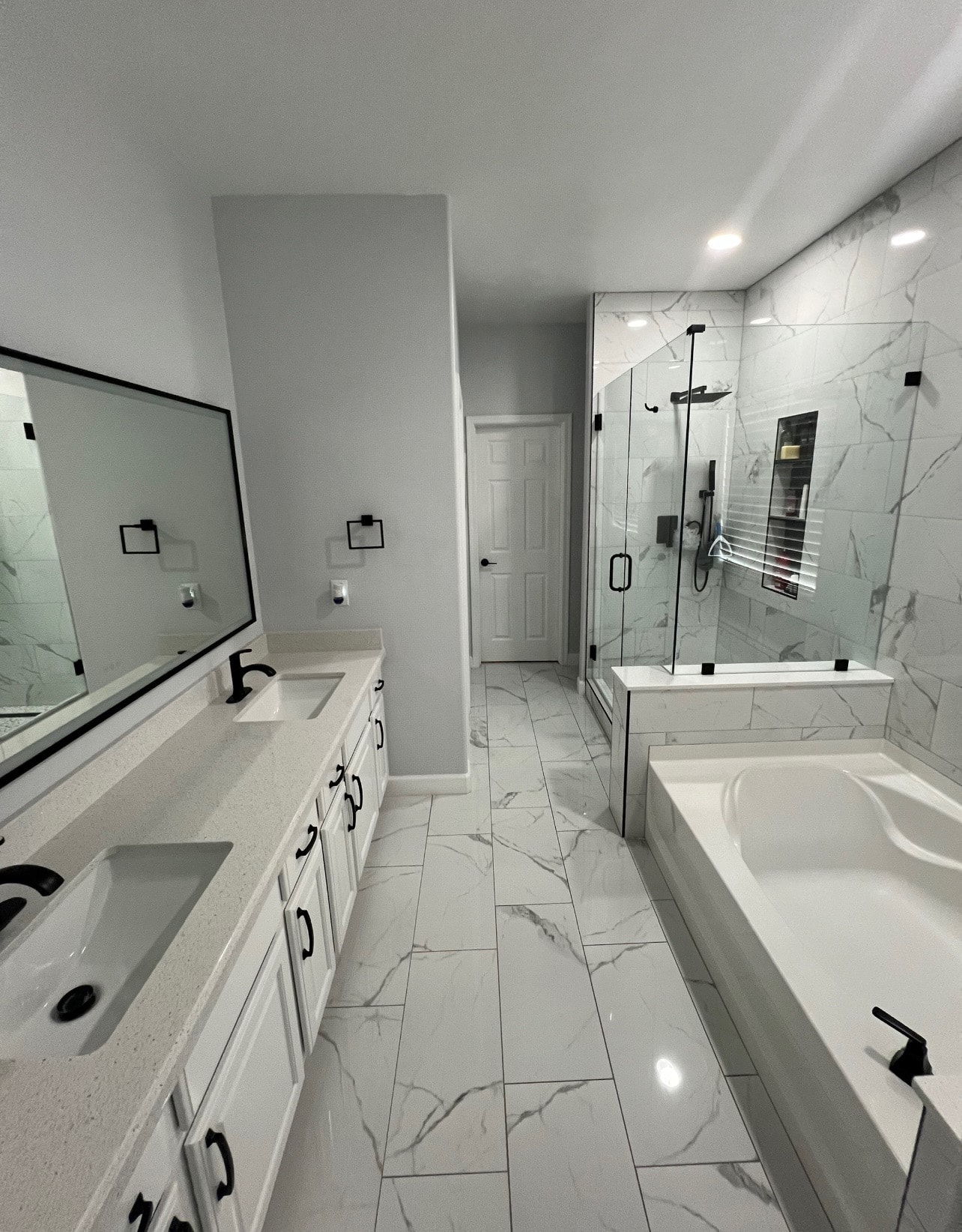 Luxury bathroom remodel with marble tile, dual vanity, glass shower enclosure, and soaking tub