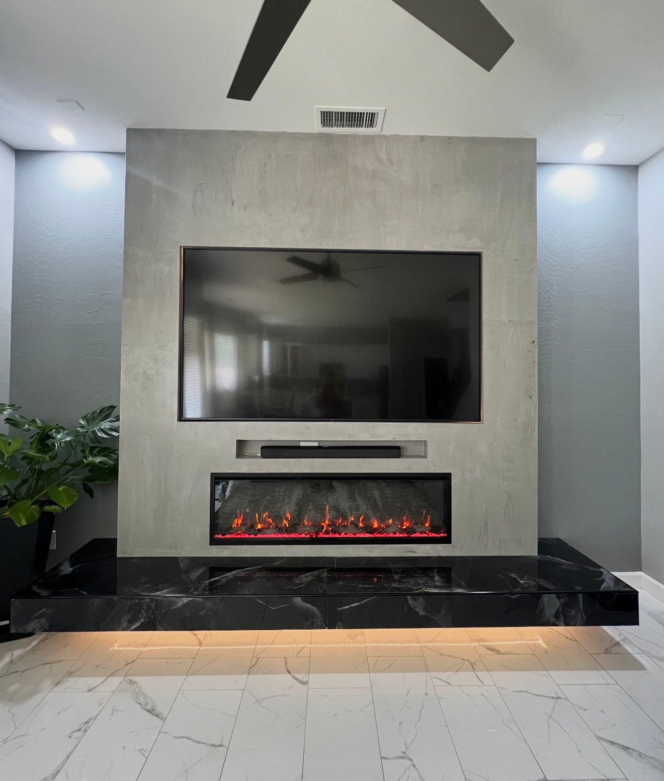 Custom fireplace and TV wall with concrete finish and marble flooring