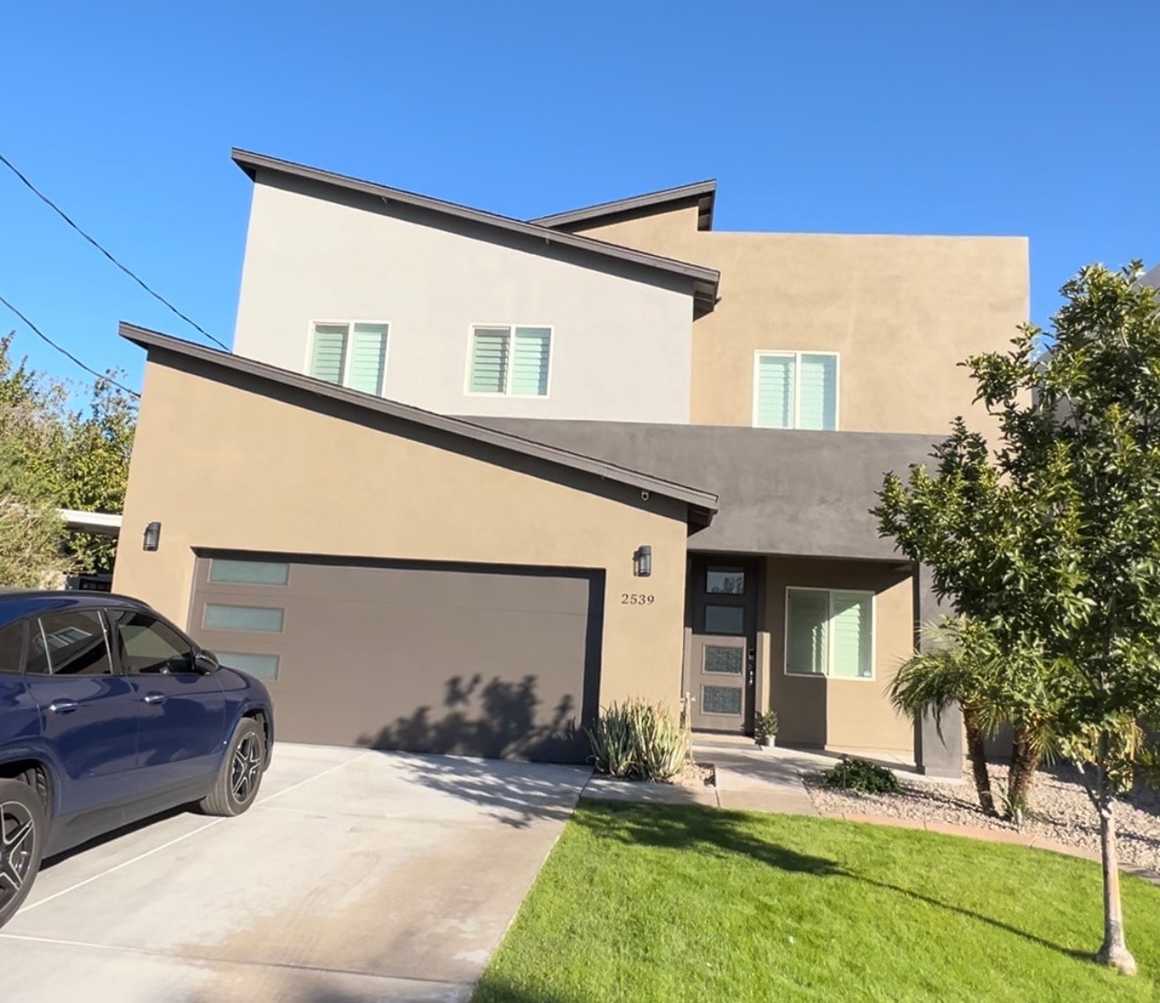 Modern two-story home exterior with stucco finish, dark trim, and contemporary garage door