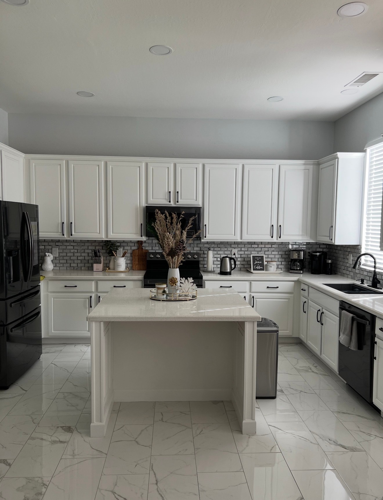 Kitchen remodel with white cabinets, marble tile floor, and subway backsplash